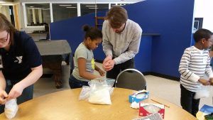 Paul Brooks, a professor in the Department of Anesthesiology, helps a student make ice cream in a bag to show how the addition of salt lowers the freezing point of water.