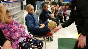 A Wildlife Defender showing a balled up armadillo to students.